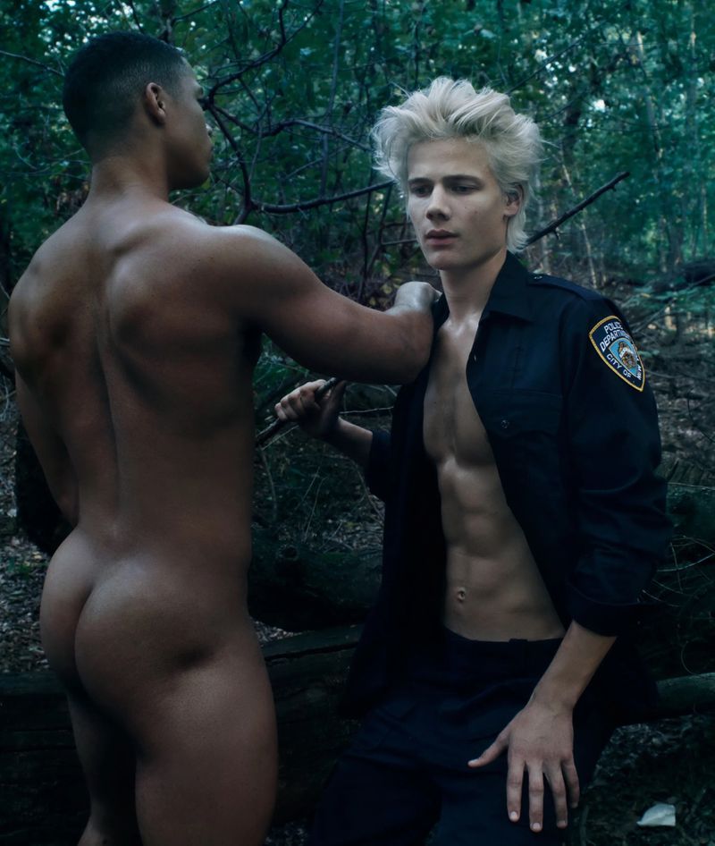 Two men in an outdoor setting: one shirtless, one in a uniform, engaging in an implied confrontation or interaction within a wooded area.