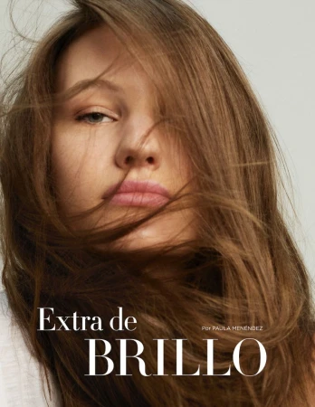 Close-up portrait of a woman with long brown hair framing her face against a plain light background