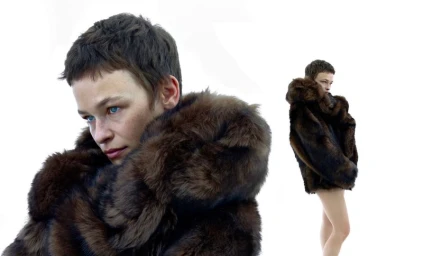 Model with short brown hair wearing a dark brown furry coat against a bright white background for Prada x Numéro Berlin