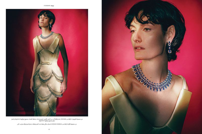 Elegant woman wearing a champagne-colored gown and sapphire jewelry, posing against a vibrant pink backdrop in a fashion editorial.