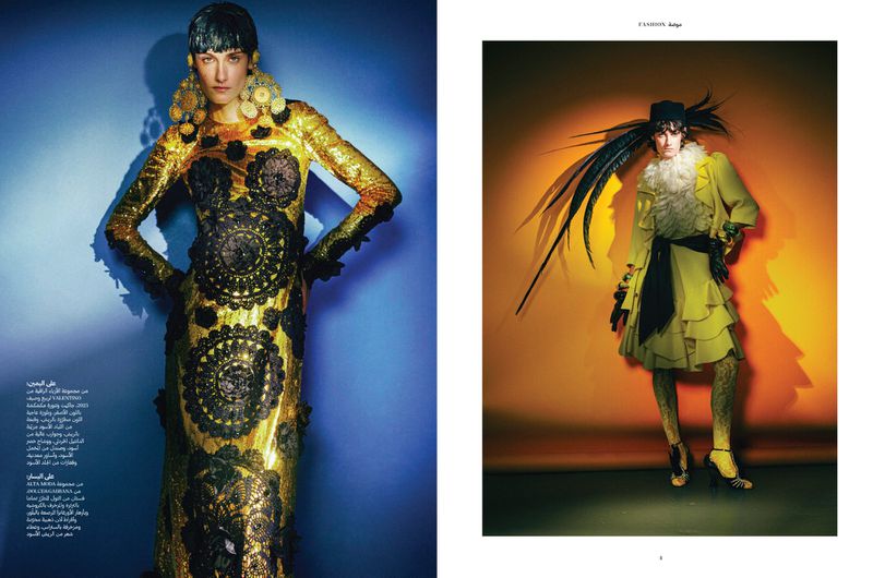 Editorial fashion spread features two women in avant-garde gold and yellow outfits with elaborate embellishments, showcasing high-fashion design.