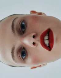 Close-up portrait of a woman with red lips and blue eyes against a light background for Spaghetti Magazine.