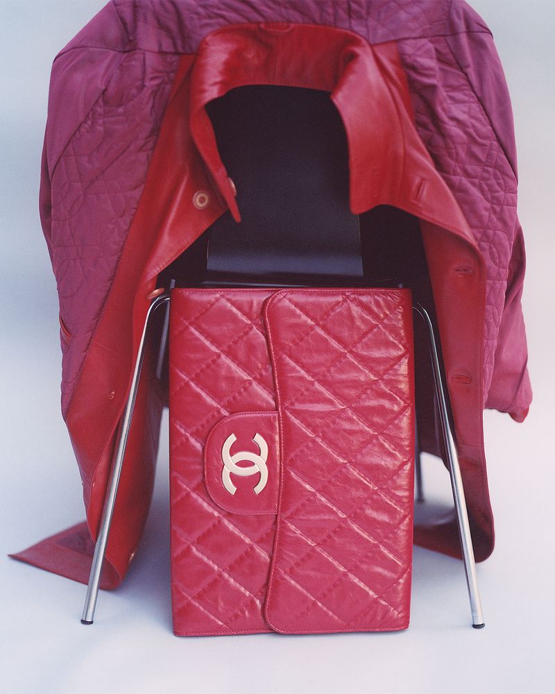 Red Chanel purse on a chair with a pink jacket draped over the back. Quilted pattern and the iconic logo are prominent.