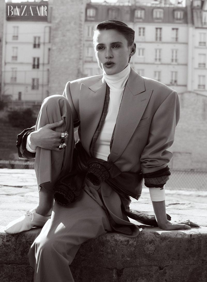 Model Aleyna Fitzgerald seated outdoors wearing a tailored suit and turtleneck for Harper's Bazaar Australia