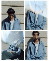 Four-panel fashion editorial grid showing a male model wearing a blue button-down shirt and white undershirt against a textured stone wall