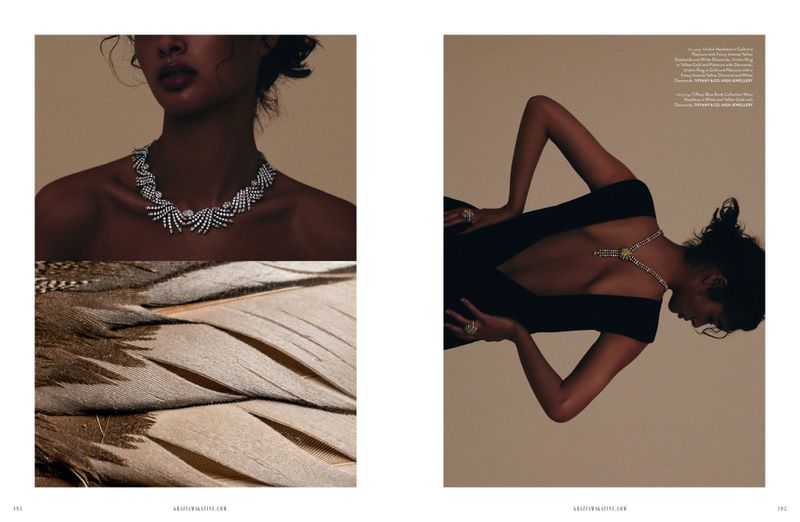 Editorial fashion shot of a woman wearing diamond jewelry with soft lighting and bird feathers, showcasing elegance and luxury.