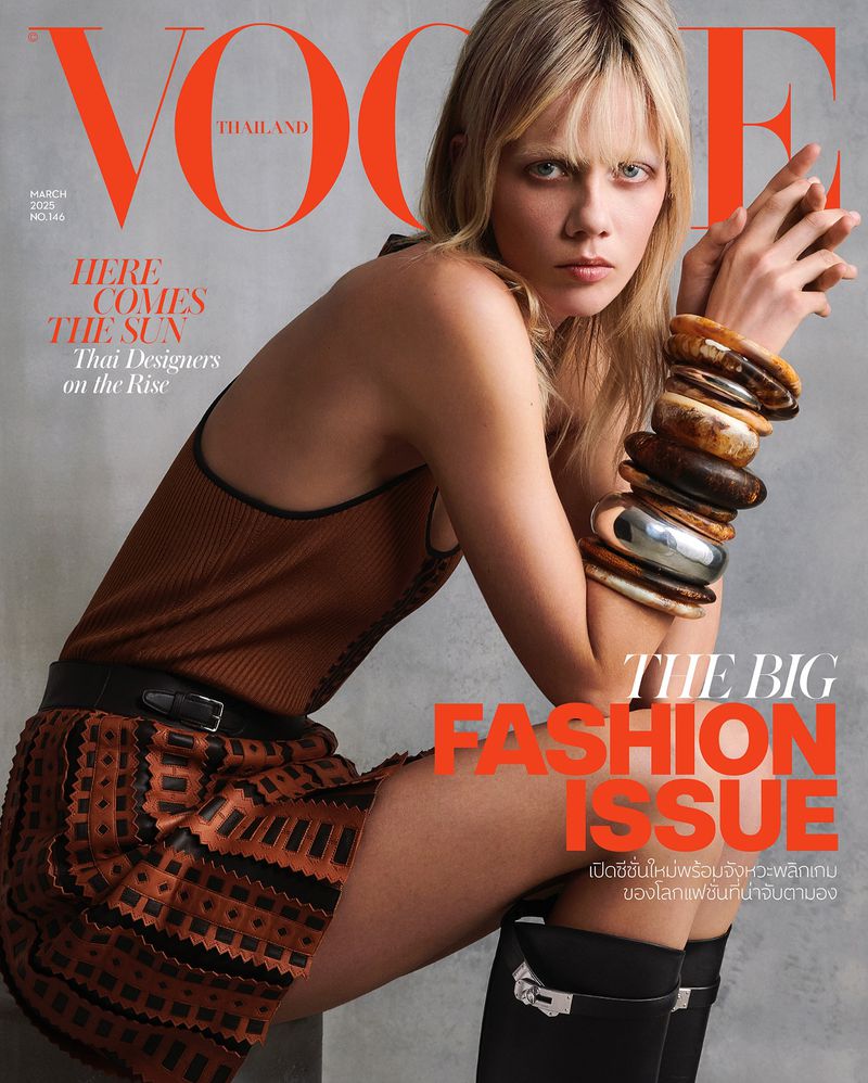 Vogue Thailand magazine cover featuring a blonde model in a brown outfit and black boots, accessorized with stacked bracelets, gazing at the camera.