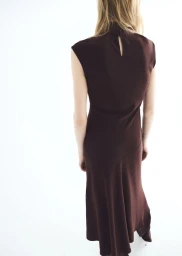 Model Jacqui Hooper seen from behind wearing a sleeveless high-neck dark brown maxi dress against a bright white background.