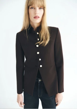 Model Jacqui Hooper wears a tailored dark brown button-up jacket and denim jeans against a bright white seamless background.