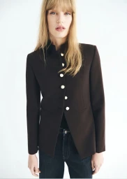 Model Jacqui Hooper wears a tailored dark brown button-up jacket and denim jeans against a bright white seamless background.