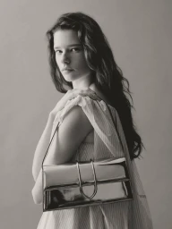Model Sandra Murray posing with a reflective metallic silver handbag wearing a striped off-shoulder top.