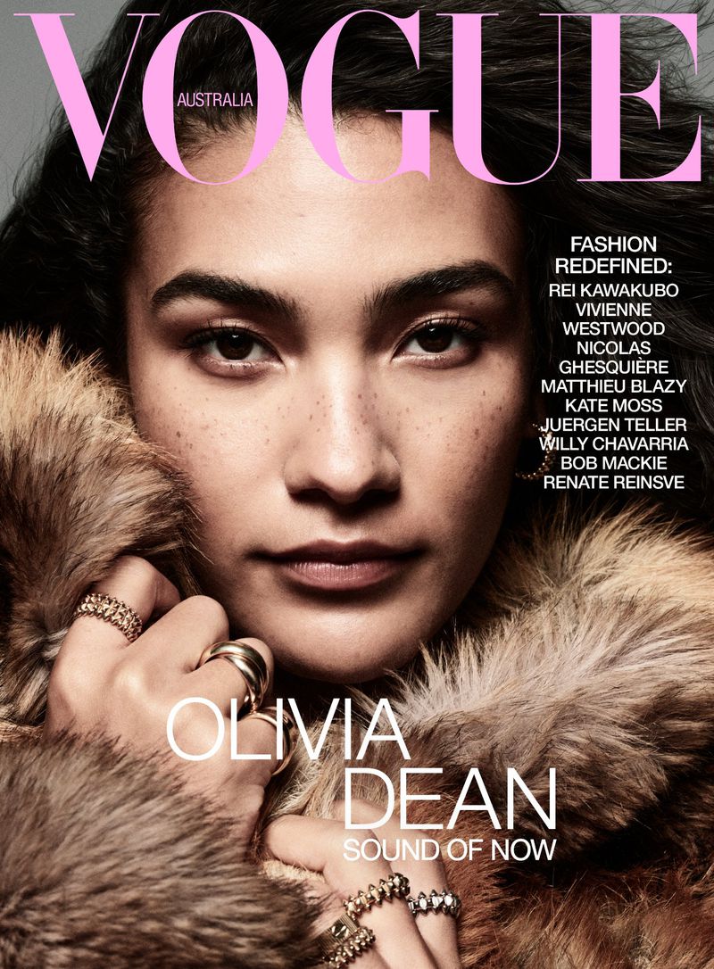 Vogue Australia cover featuring Olivia Dean wearing a fur coat and rings; the magazine title and fashion designer credits are visible.