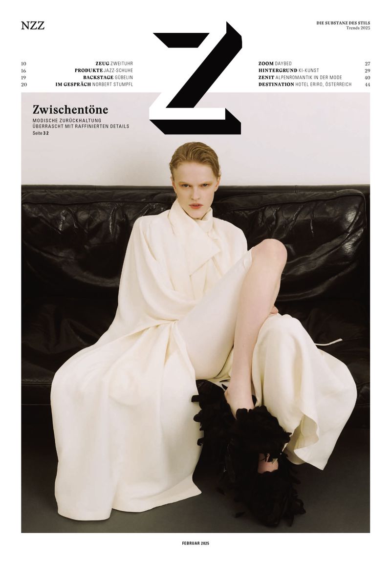 Fashion magazine cover featuring model in white outfit and black shoes, seated on black couch against a neutral background.