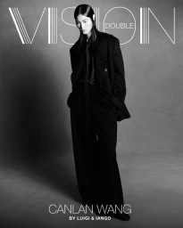 Canlan Wang posing in an oversized black tailored suit and tie against a studio backdrop for Double Vision magazine.