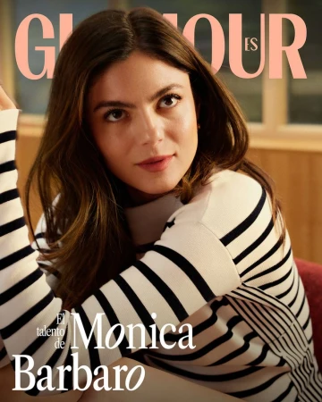 Glamour ES magazine cover featuring Monica Barbaro, fair-skinned brunette woman, wearing a striped sweater in soft, diffused lighting.