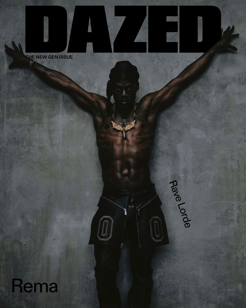 Rema poses for a Dazed magazine cover with his arms outstretched against a textured gray background, adorned with a gold necklace.