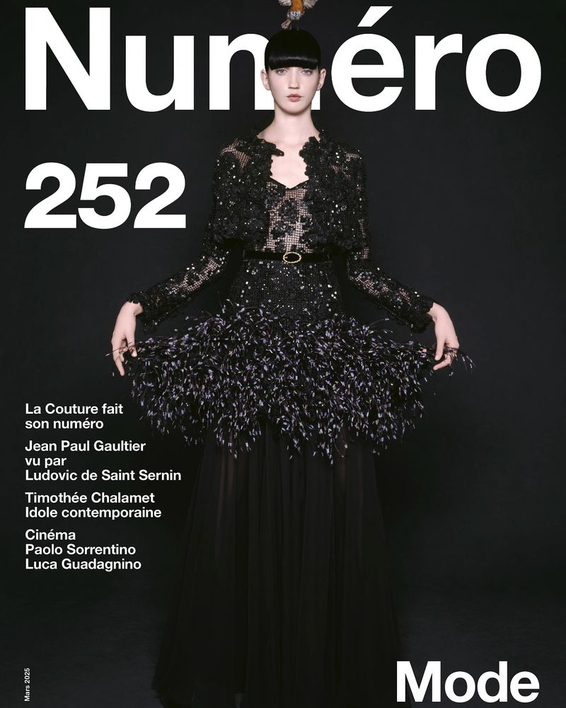 Magazine cover featuring a model in a black feathered gown and jacket, shot against a dark background with prominent white magazine text.