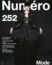 Model in black lace and feathered couture gown against a dark background for Numero France magazine cover.