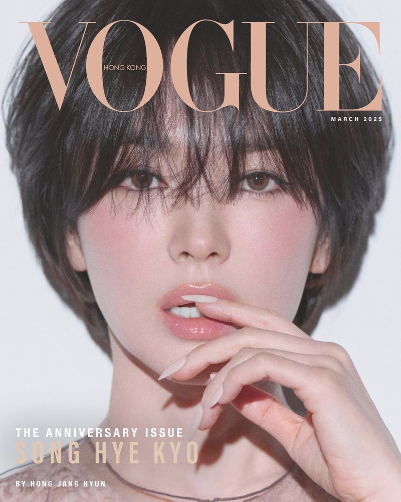 Vogue cover featuring a close-up portrait of a woman with short dark hair, wearing a neutral top, and light pink blush against a white backdrop.