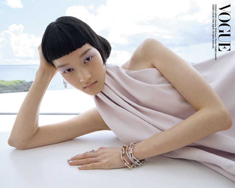 Elegant Asian woman in Vogue Japan, January 2005 issue, wearing light pink dress and jewelry, posing against a serene ocean backdrop.