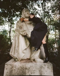 Model embracing a weathered stone statue in a park for a Twin Magazine fashion editorial by Arno Frugier.