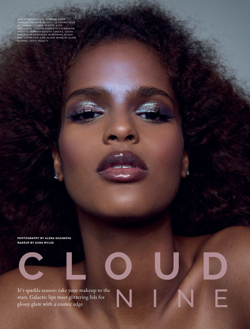 Close-up fashion portrait of a woman with silver eyeshadow and glossy lips against a neutral gray background in a studio.
