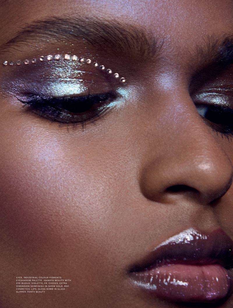Macro beauty close-up of a model featuring rhinestone eye embellishments, metallic duochrome eyeshadow, and high-shine lip gloss.