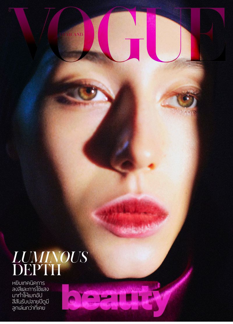Close-up of a woman's face on the cover of Vogue Thailand magazine, featuring luminous skin, red lips, and a dark purple head covering.