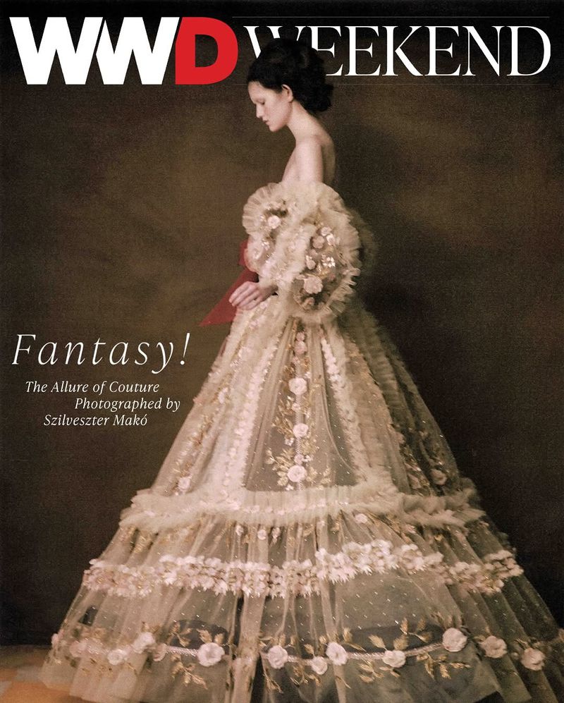 Fashion magazine cover featuring a woman in an elaborate couture gown with floral embroidery and tulle ruffles against a dark backdrop.