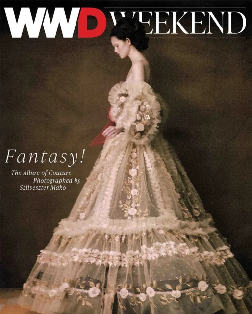 Fashion magazine cover featuring a woman in an elaborate couture gown with floral embroidery and tulle ruffles against a dark backdrop.