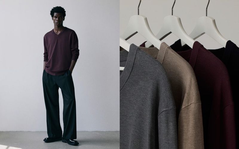 Dark-skinned male model poses in a maroon v-neck sweater and dark slacks. Sweaters hang on hangers, contrasting against a neutral background.