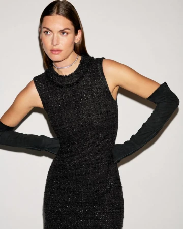 Model wearing a sleeveless black tweed dress paired with long black opera gloves and a sparkling choker against a light studio backdrop.