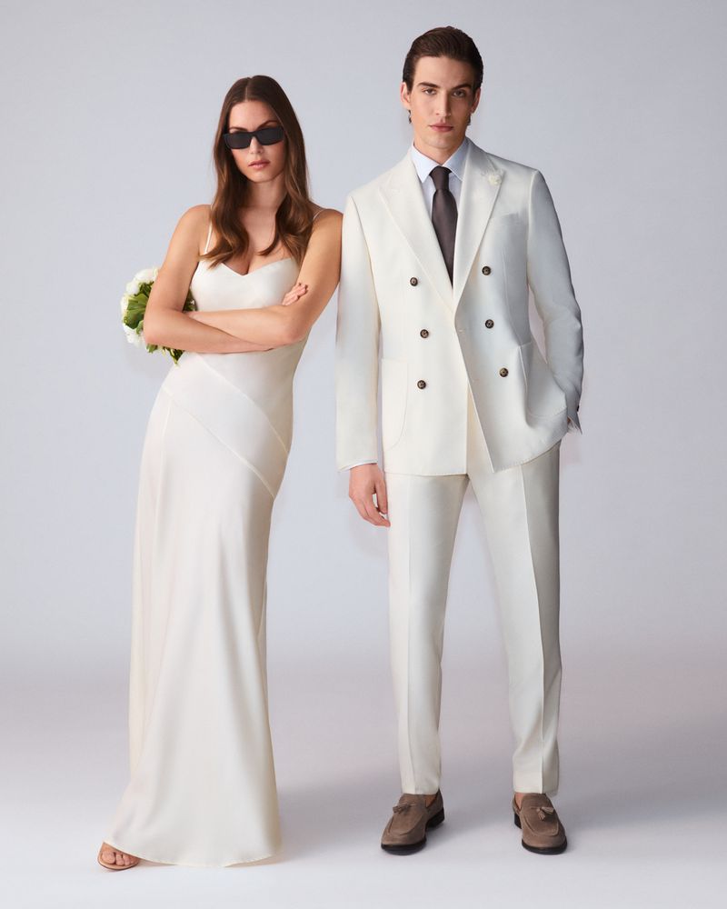 Model in white dress standing next to a man in a white suit against a neutral background for Joop Lookbook S/S 26