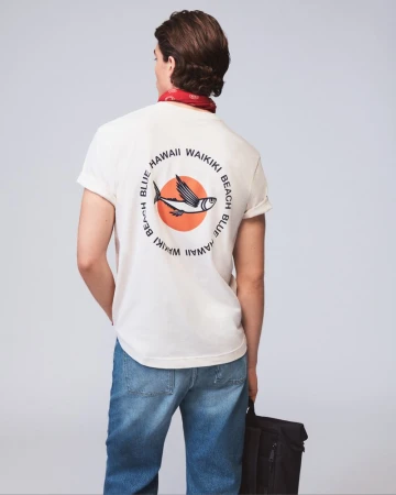 Back view of a man wearing a white t-shirt with a graphic print, blue jeans, and a red bandana, holding a black bag.