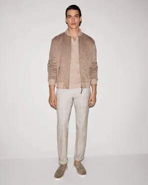Amerigo Valenti wearing a beige bomber jacket, matching knit top, and light trousers against a neutral studio backdrop.