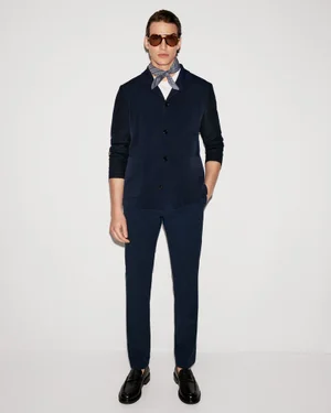 Model Amerigo Valenti wearing a navy blue overshirt jacket, matching trousers, neck scarf, and sunglasses against a white backdrop.