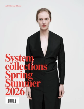 Fashion magazine cover with a model wearing a black blazer dress against a white background with red typography and clean studio lighting.