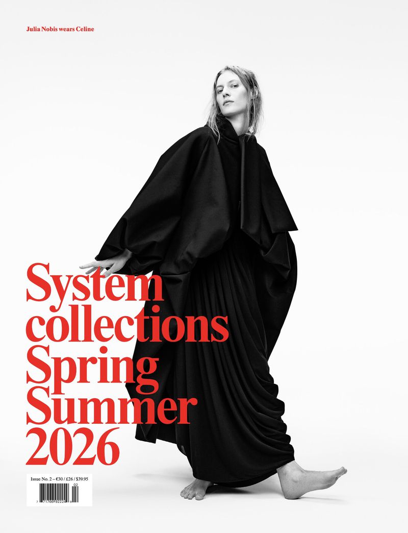 Fashion model Julia Nobis in a black dress and shawl poses against a white background for a magazine cover promoting Spring/Summer 2026 collections.