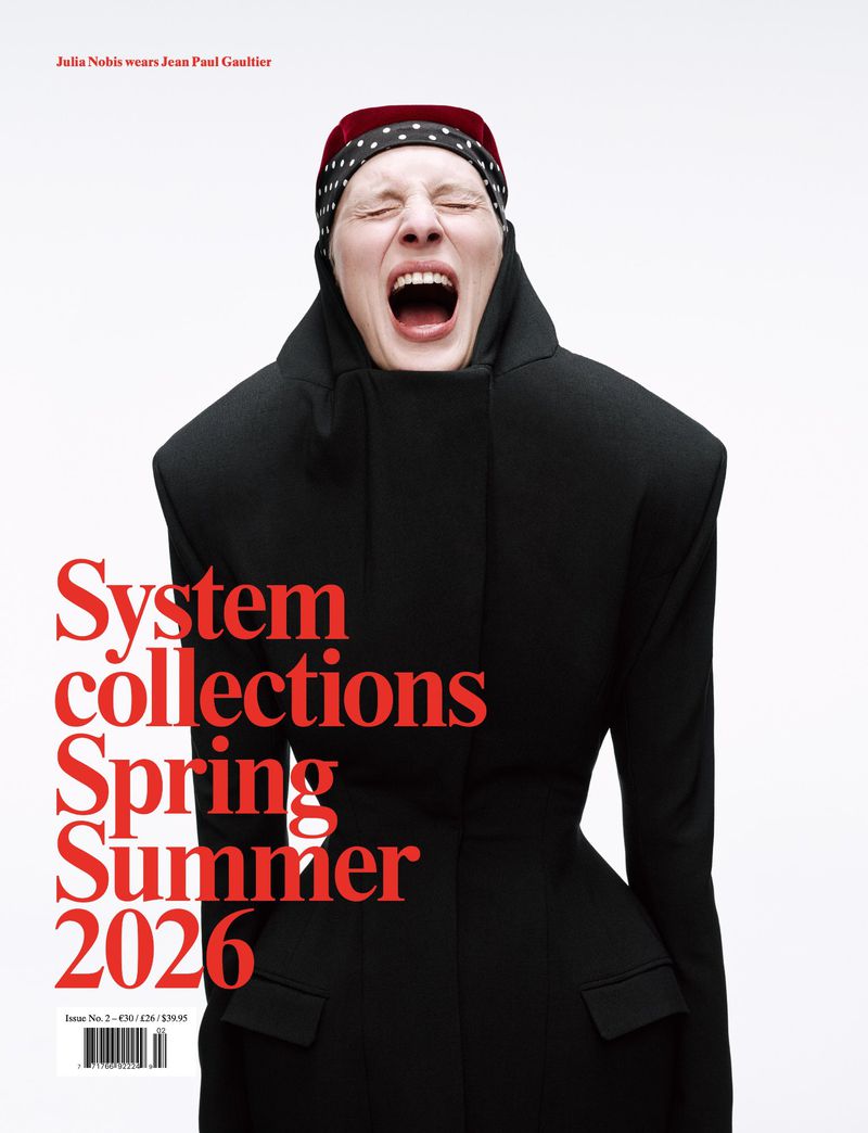 Fashion magazine cover featuring a woman in a black jacket and polka-dot headscarf, screaming with her mouth wide open against a white background.