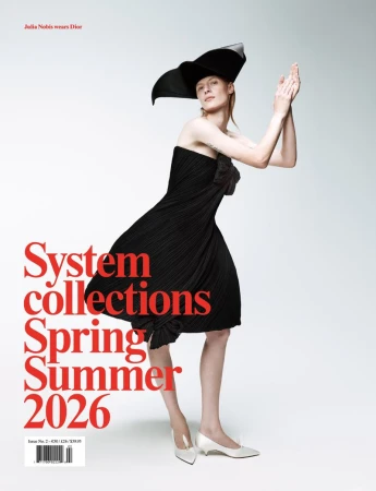 A slender woman with pale skin poses with her hands raised wearing a black dress and hat on a white backdrop. Red text overlays.
