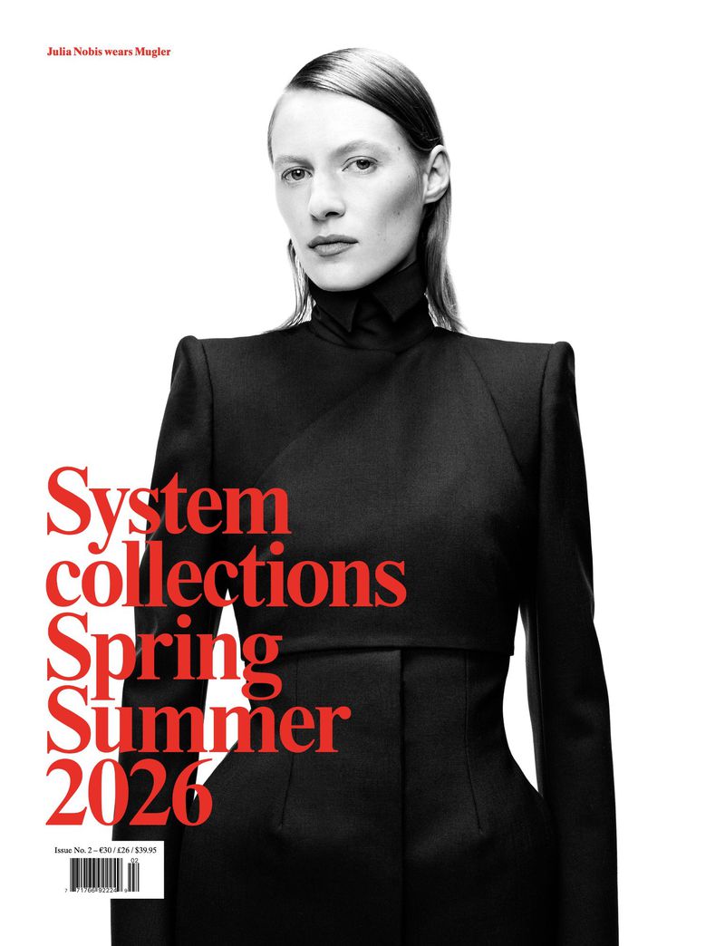 Fashion magazine cover featuring a fair-skinned woman with slicked-back hair wearing a black Mugler suit against a white backdrop.
