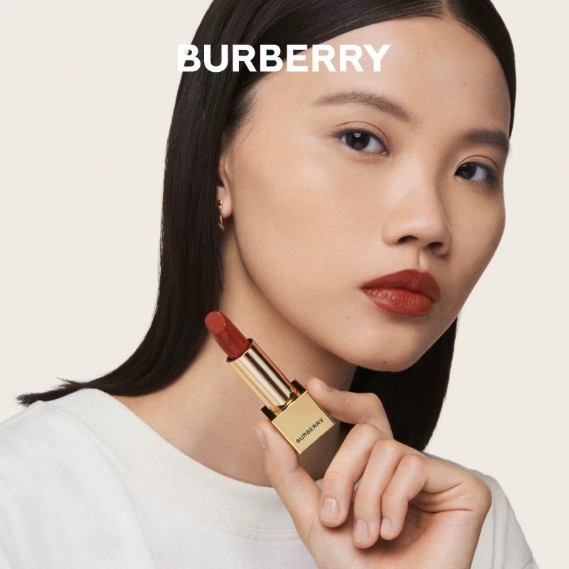 Model holding a gold lipstick tube against a plain background for Burberry Evergreen campaign