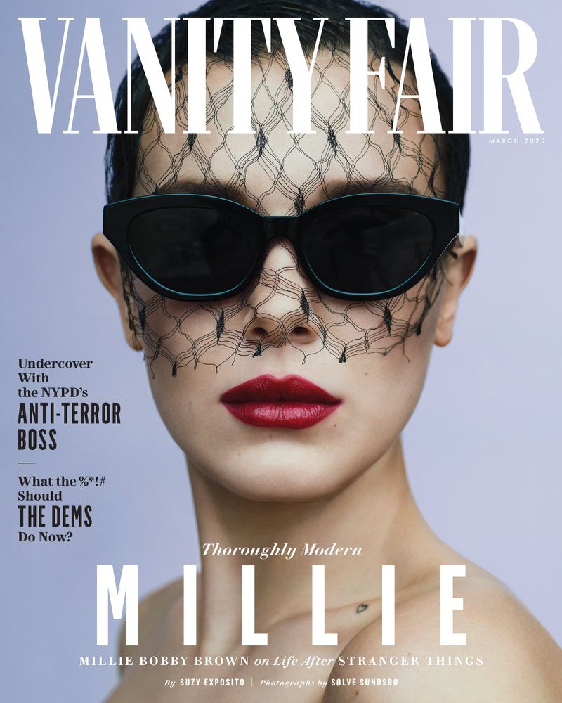 Vanity Fair cover featuring Millie Bobby Brown with red lipstick and sunglasses with mesh face covering on a light purple background.