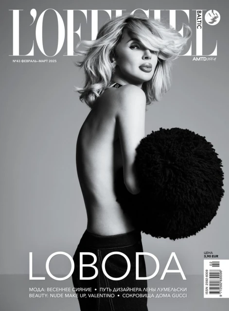 L'Officiel Baltic magazine cover featuring a bare-shouldered woman with blonde hair, jeans, and a black fluffy accessory against a gray background.