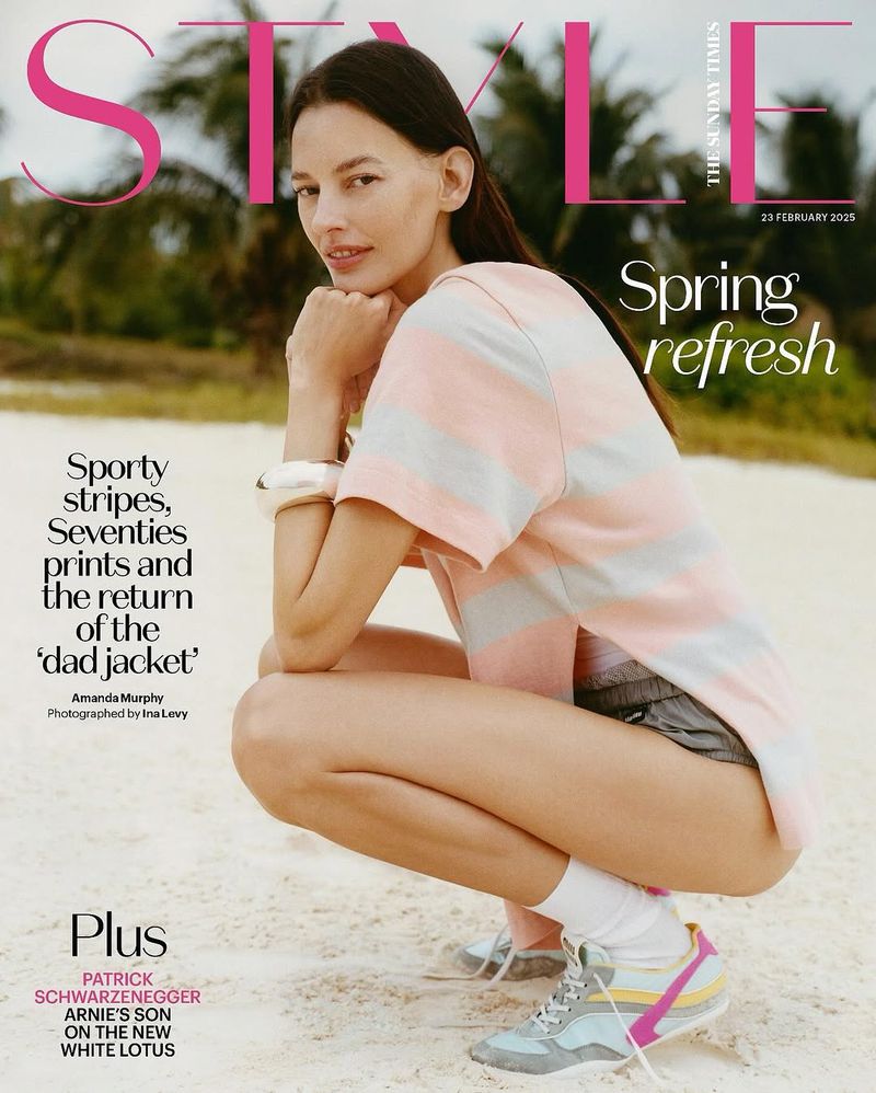 Fashion editorial magazine cover featuring a model squatting on a beach wearing a striped t-shirt and athletic sneakers.