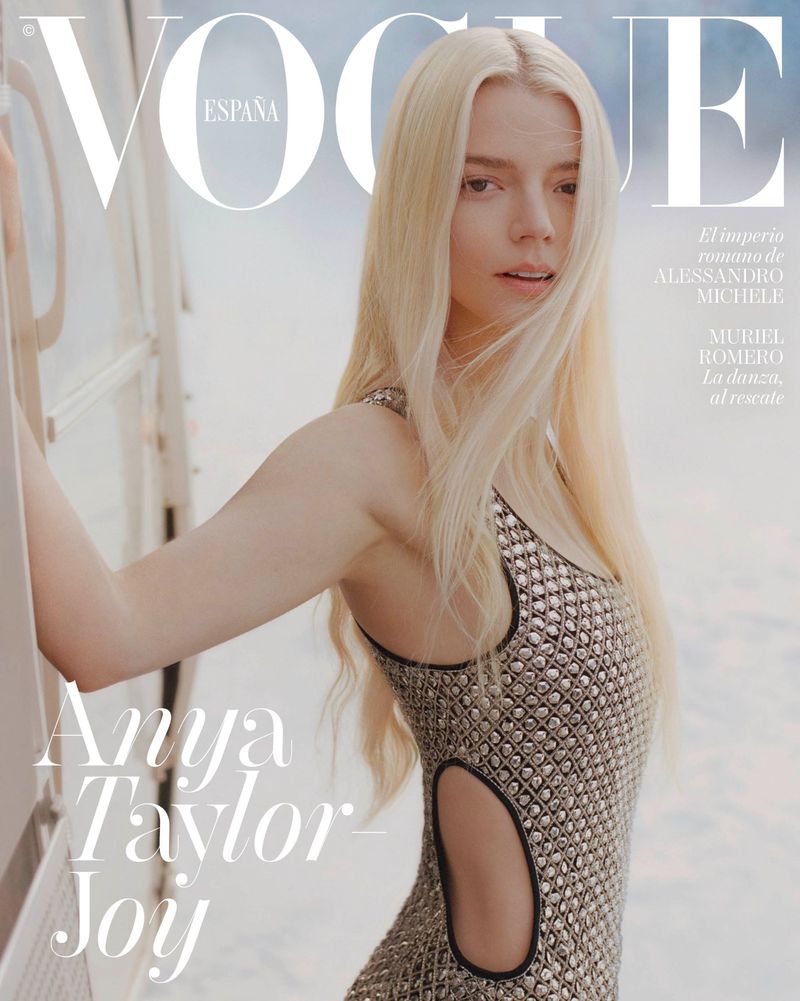 Vogue Espana cover featuring Anya Taylor-Joy, wearing a silver cut-out dress, standing next to a white structure with a light blue background.