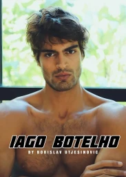 Portrait of male model Iago Botelho shirtless with crossed arms against a softly blurred green window background.