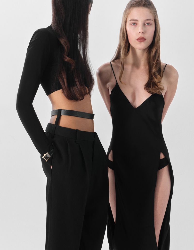 Two women pose in fashionable black dresses against a white backdrop, showcasing sleek lines and modern design elements.