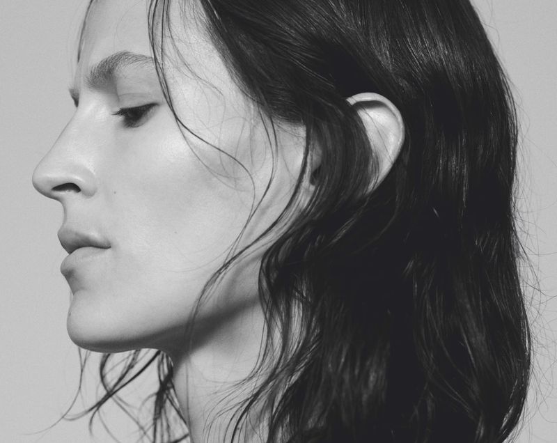 Black and white profile close-up of model Jeanne Cadieu with dark wavy hair against a pale background.
