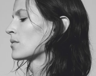 Black and white profile close-up of model Jeanne Cadieu with dark wavy hair against a pale background.